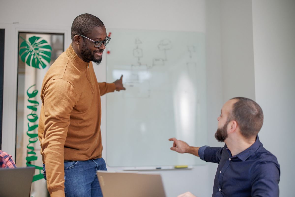 Un membre de l'équipe Fair3 explique un schéma au tableau blanc à un collègue